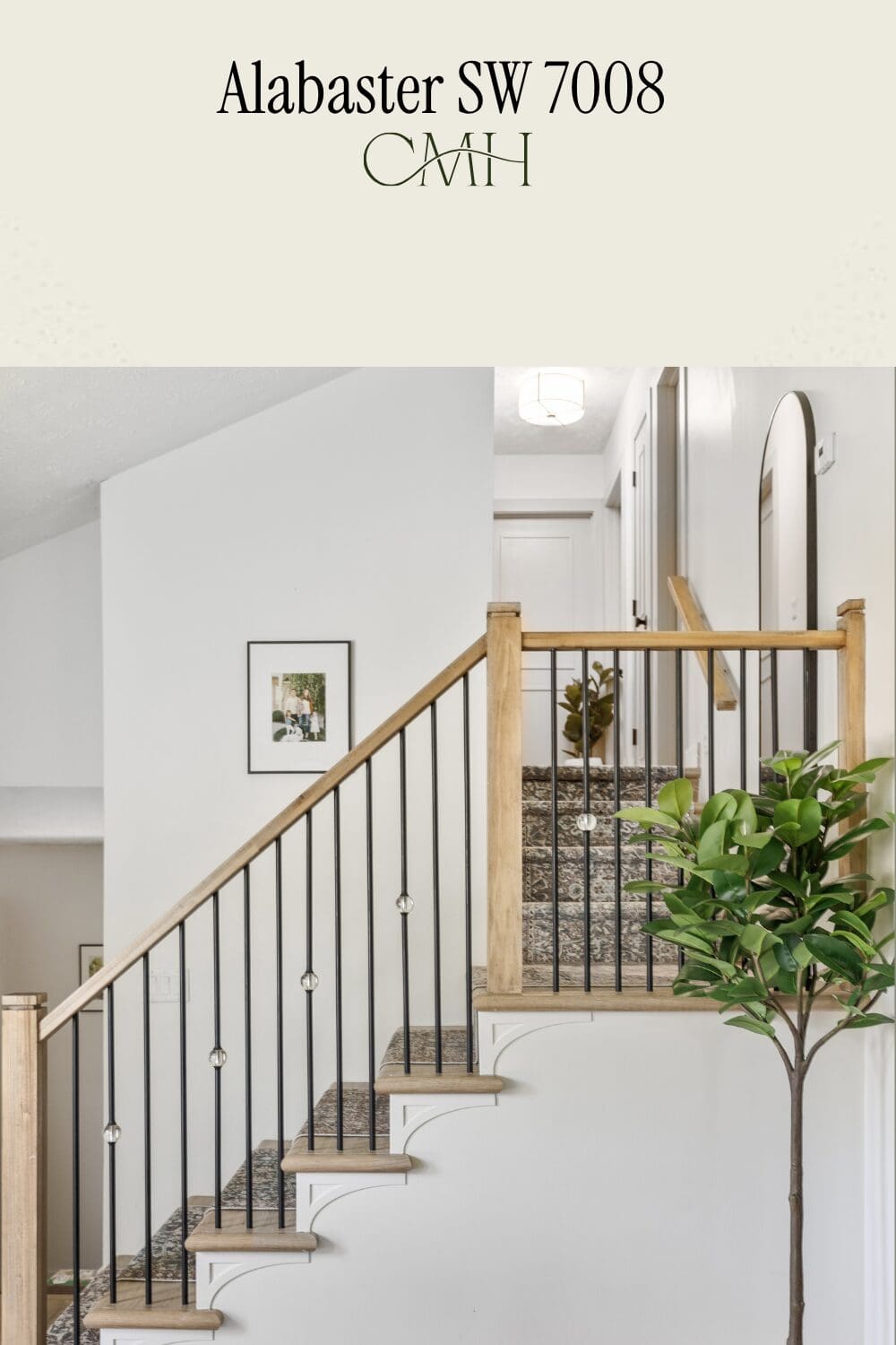 SW 7008 Alabaster paint color on staircase walls with wood and black iron railing and patterned stair runner