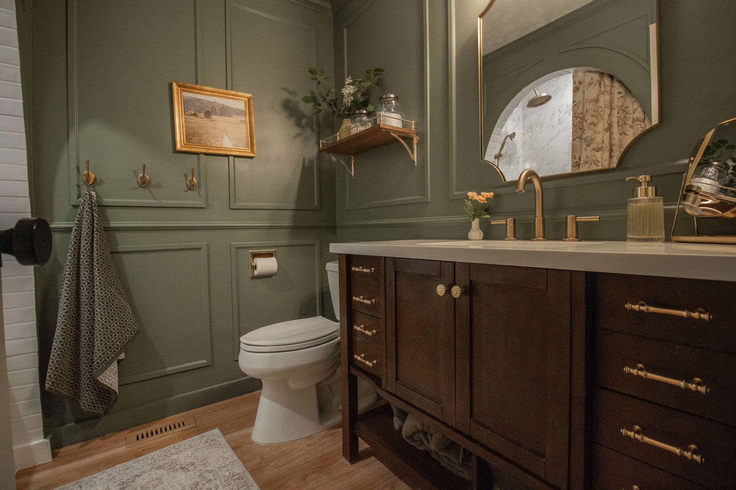 Sherwin Williams Dried Thyme on bathroom walls with dark wood vanity, gold hardware and arched mirror
