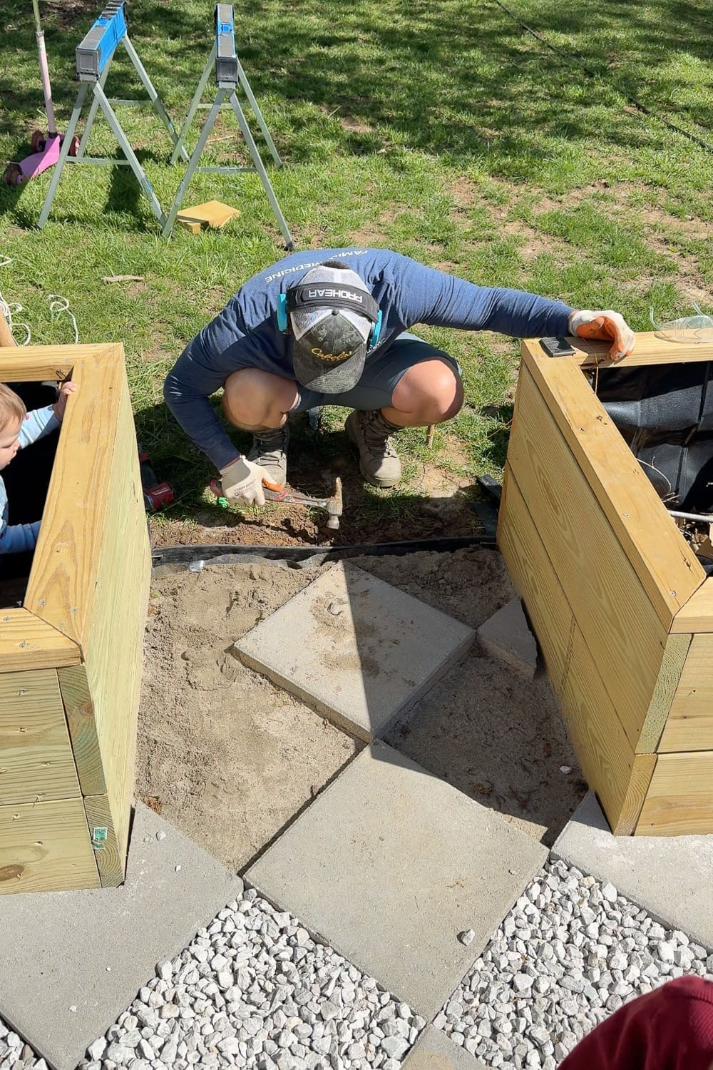 Hammering landscape edging into place around the perimeter of a diamond pattern paver walkway to contain the gravel and pavers