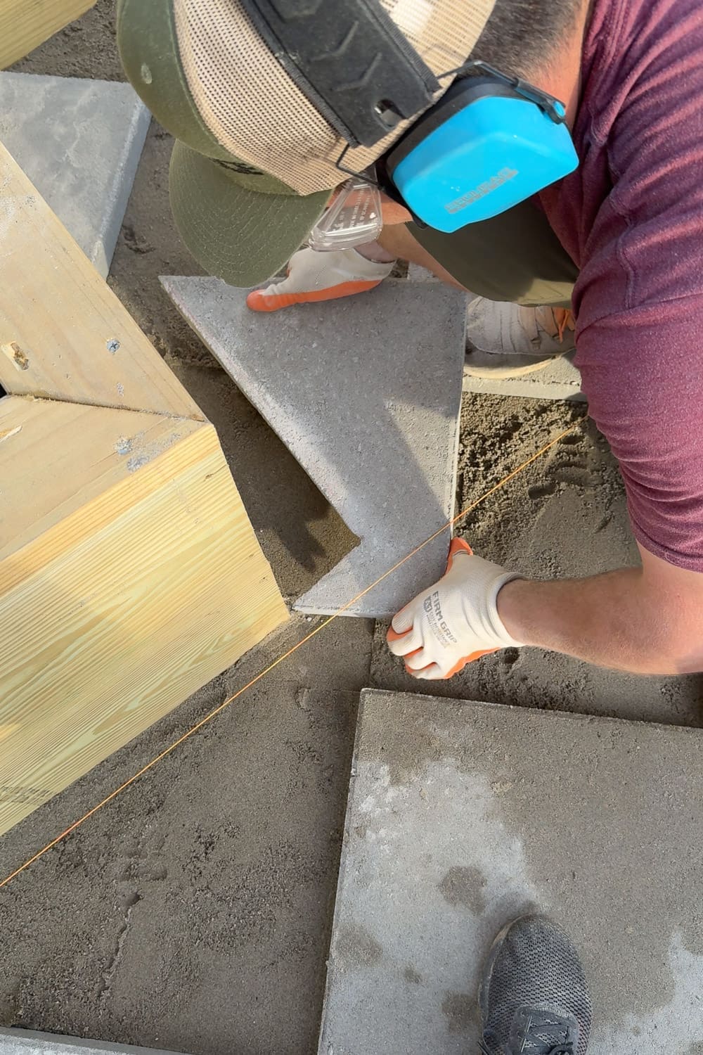 Marking a concrete paver for a custom diagonal cut along the string line to fit it snugly against a raised garden box corner