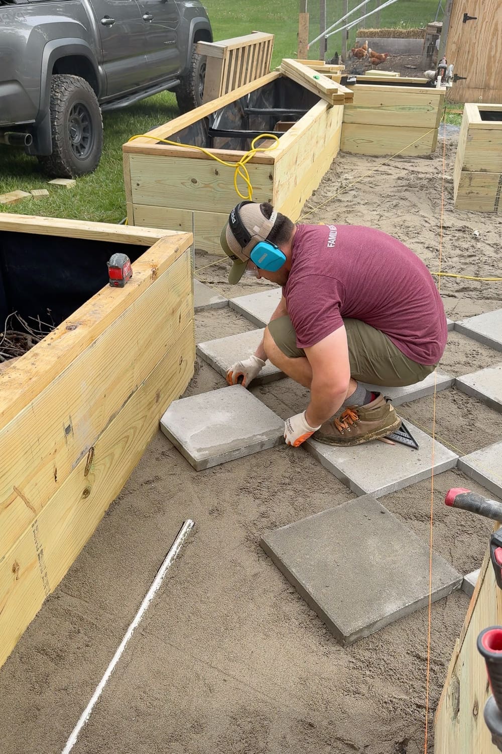 Placing square pavers in a checkerboard diamond pattern using a carpenter's square to keep each paver perfectly aligned and evenly spaced