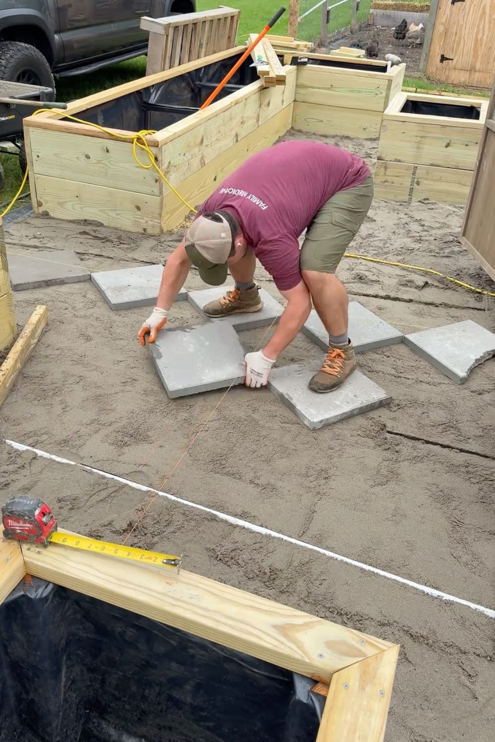 Carefully placing square pavers along a string line with a tape measure to keep consistent spacing between each paver for the diamond pattern