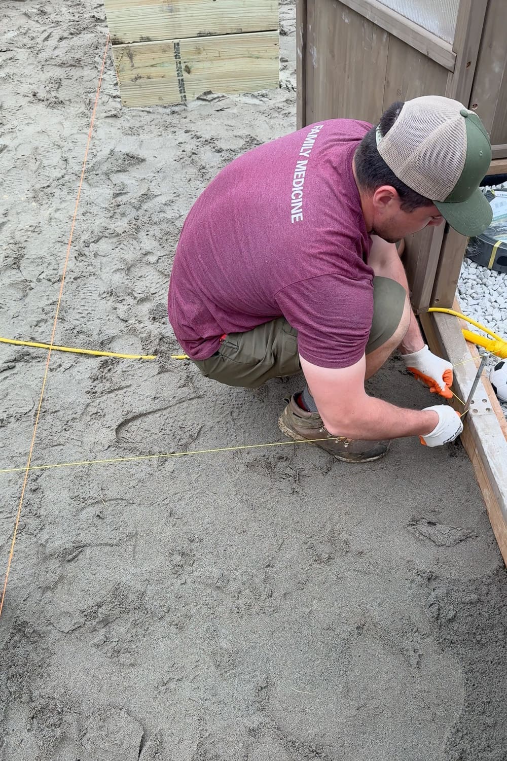 Setting up string lines across the leveled sand base to create a grid for laying square pavers in a checkerboard pattern