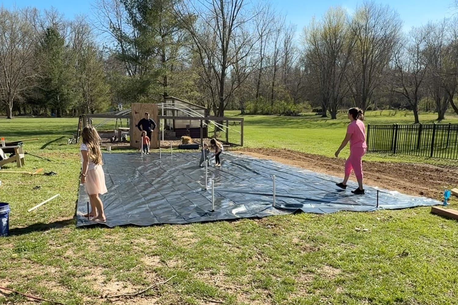 Black plastic weed barrier fully laid out across garden area with irrigation pipes and layout in place