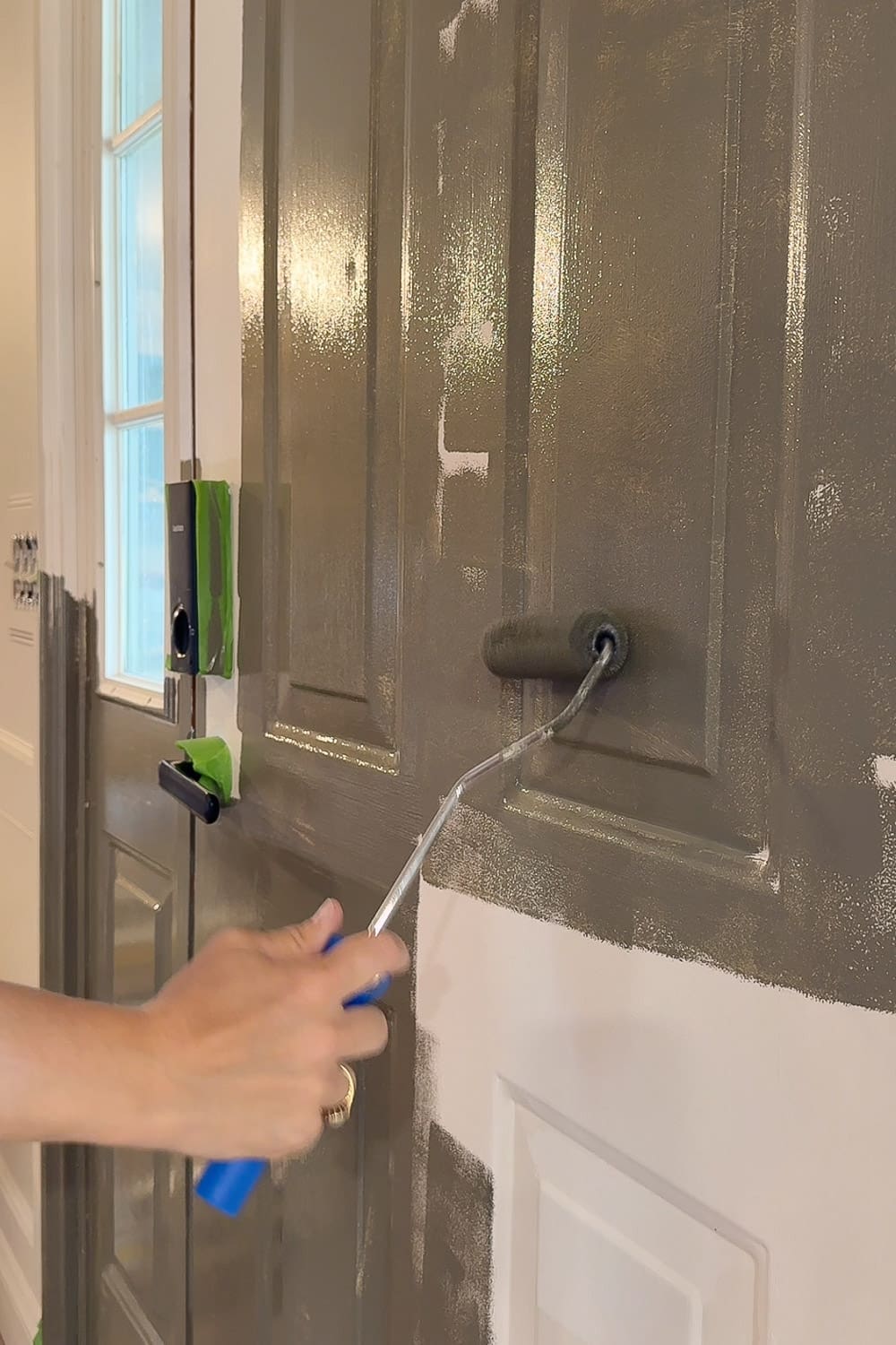 Rolling green (Sherwin-Williams Hidden Trail) paint onto the front door.