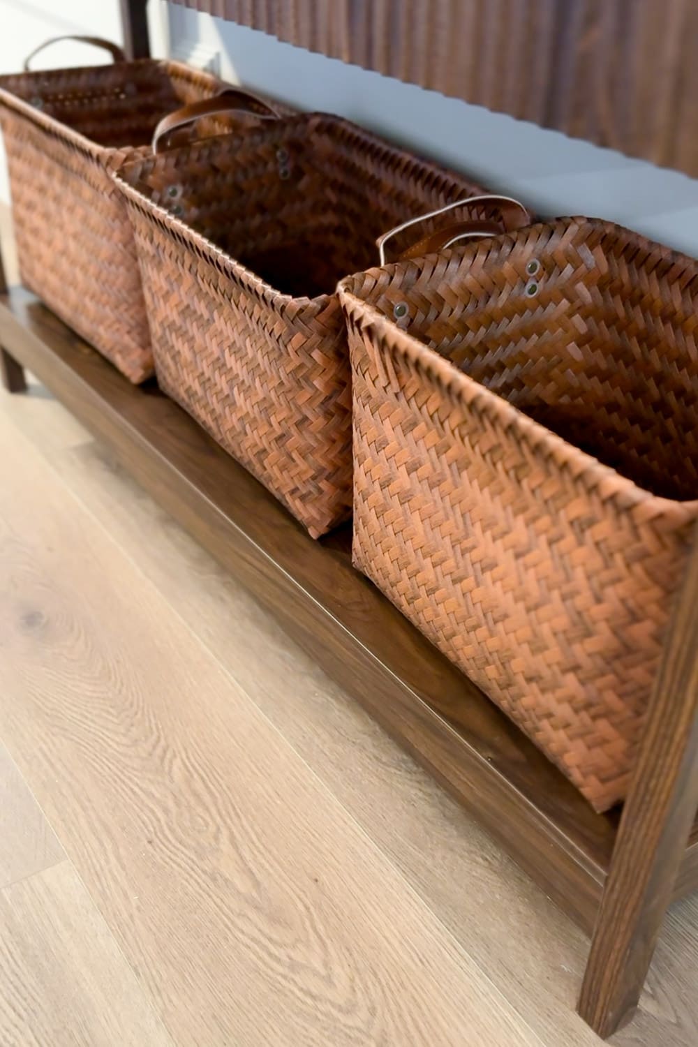 Woven brown storage baskets tucked under a dark wood console table for stylish and functional entryway table decor