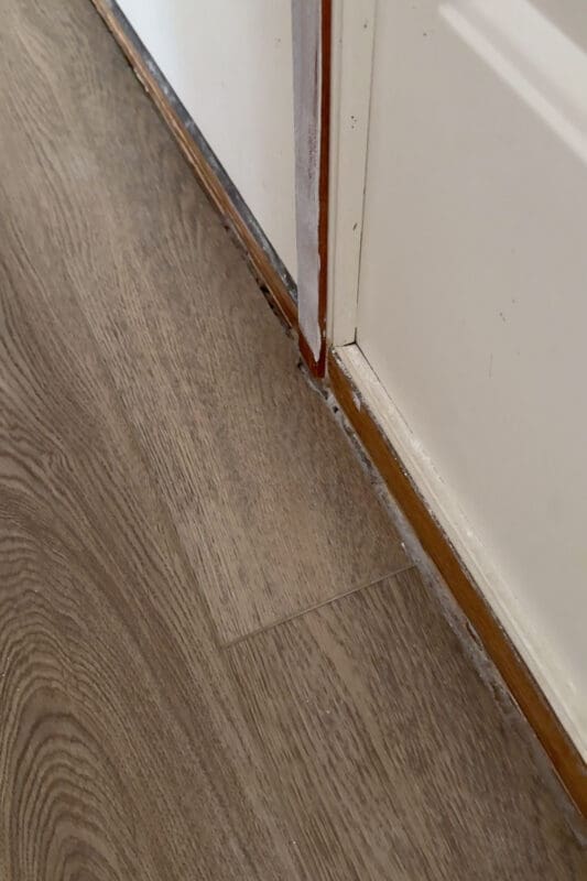 Close-up of the gap between flooring and the front door before installing new trim.