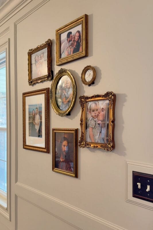 Entryway wall decor featuring a curated gallery wall of vintage gold frames with family photos in varied sizes and shapes
