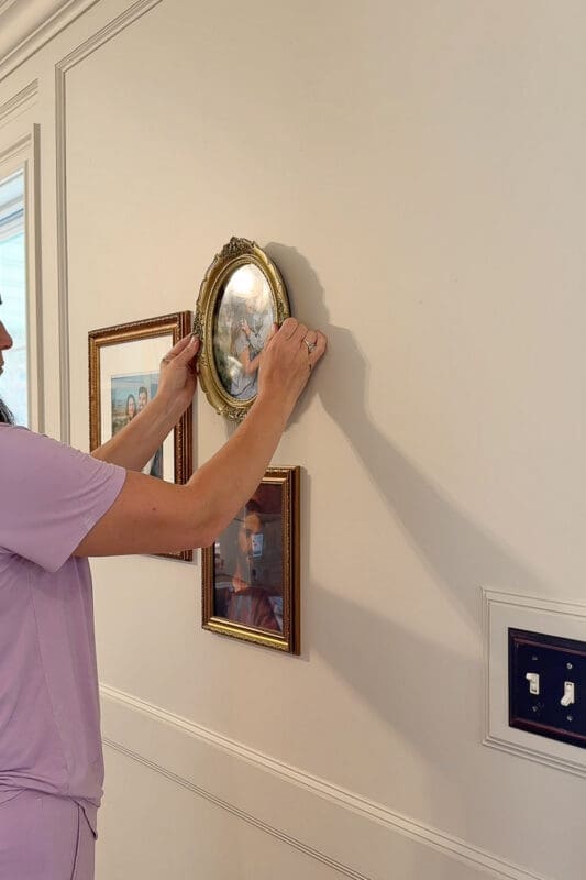 Hanging vintage gold-framed family photos to create a gallery wall as part of an entryway wall decor project