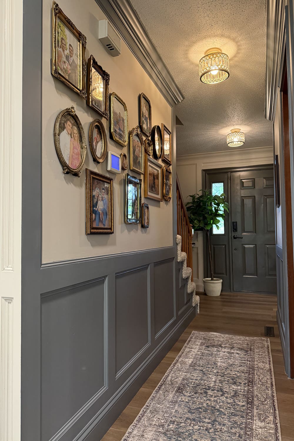 Finished narrow hallway makeover with a mismatched gold gallery wall, Taiga moulding, Accessible Beige walls, and a runner leading to a dark front door