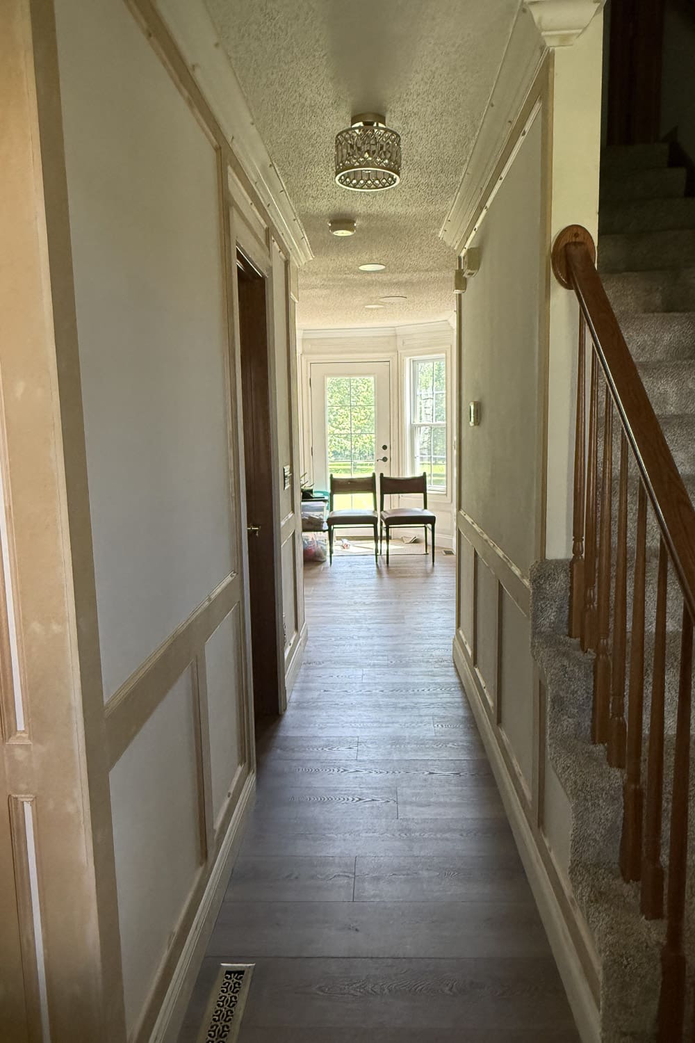 Narrow hallway before makeover with plain beige walls, unpainted trim, and a dated light fixture