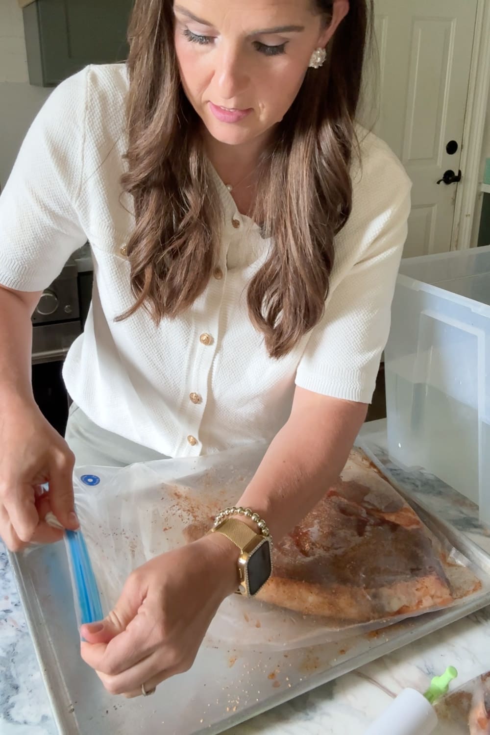 Sealing a seasoned bone-in steak into a zip-top bag to prepare it for sous vide cooking