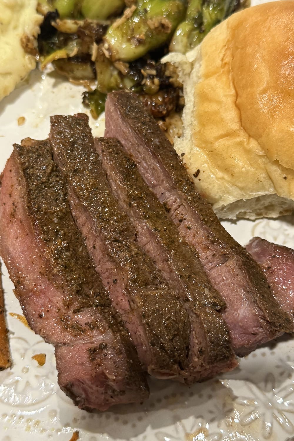 Close-up of sliced sous vide steak showing an even pink interior and seasoned crust, plated with sides