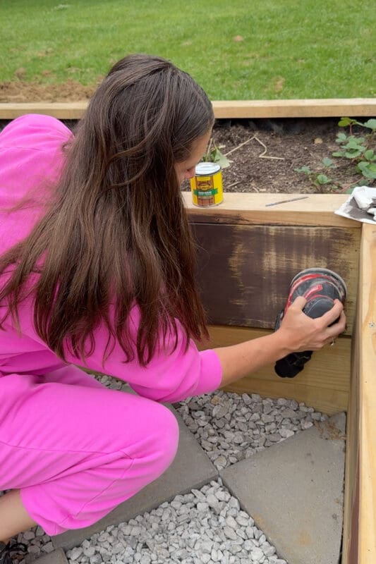Woman sanding pressure treated wood before applying minwax stain