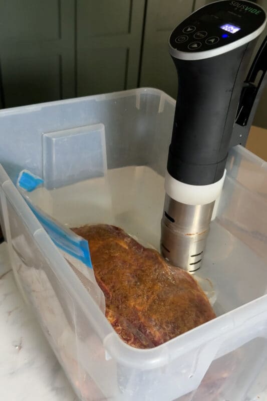 Seasoned chuck roast in a sealed bag fully submerged in the water bath with the circulator running, cooking sous vide