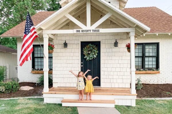 two little girls celebrating on the finished DIY front porch with gable roof