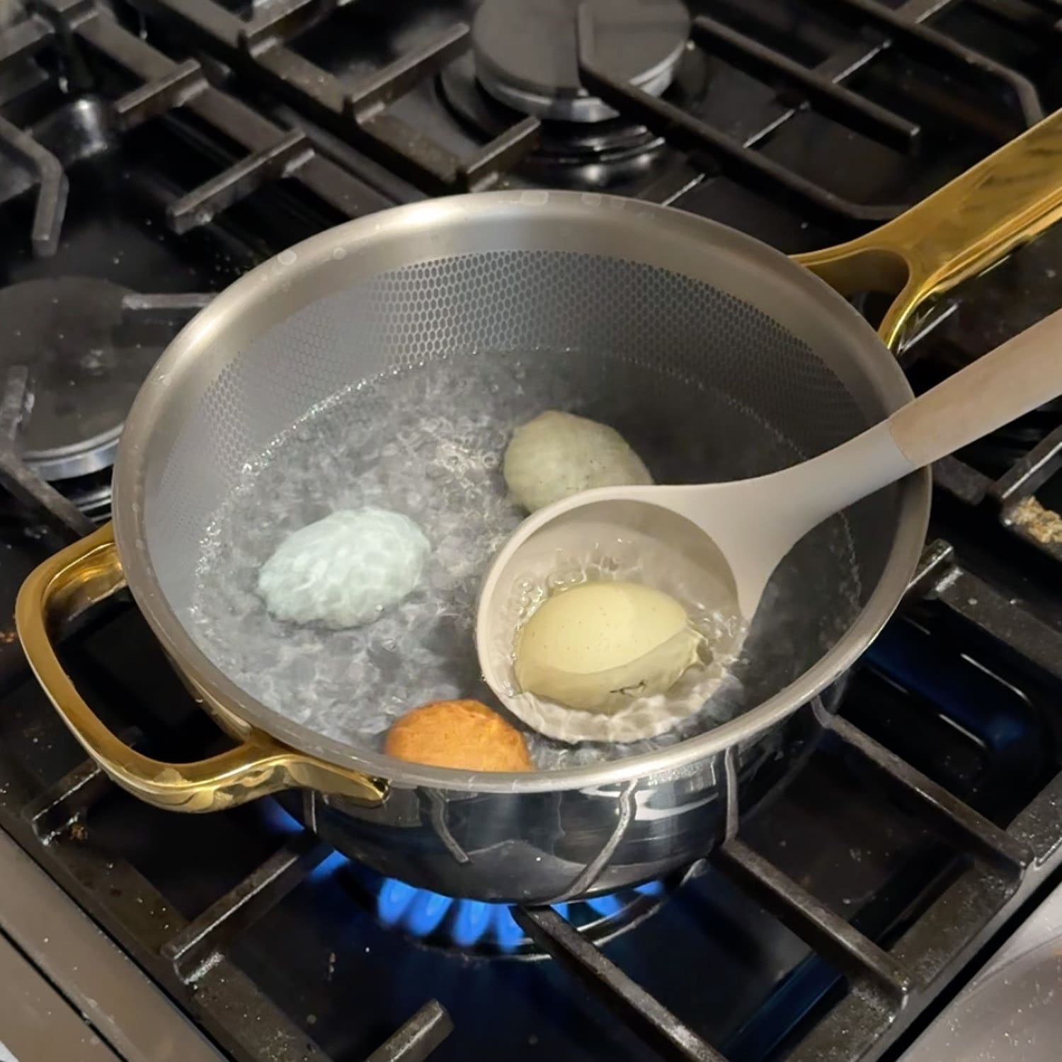 Crystel lowering fresh eggs in green, white, and brown shells into a pot of boiling water with a slotted spoon, the step-by-step method for hard boiling fresh eggs so they peel easily.