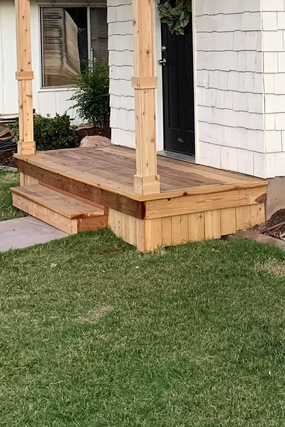 Finished redwood box step and wood-wrapped porch base at the corner of a DIY front porch.