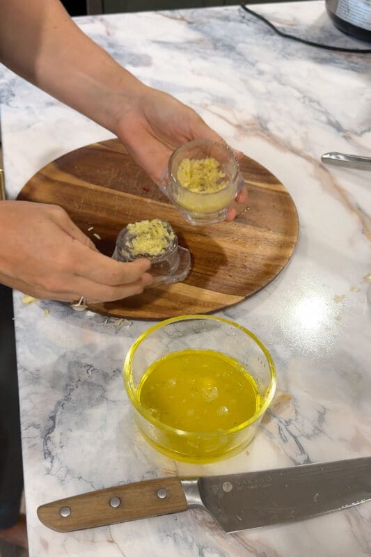 Crystel scooping minced garlic from a handheld garlic twister