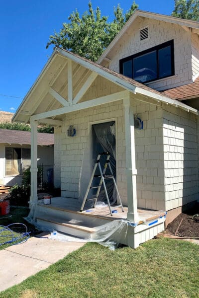 Freshly painted white gable porch roof with the front door masked off