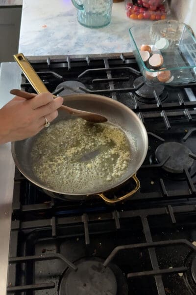 Crystel stirring finely minced garlic sizzling in melted butter and olive oil with a wooden spoon