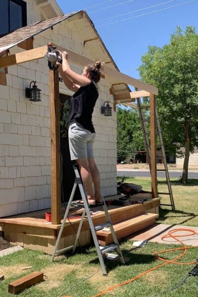 Cutting the header board while building a porch roof flat frame over the front door