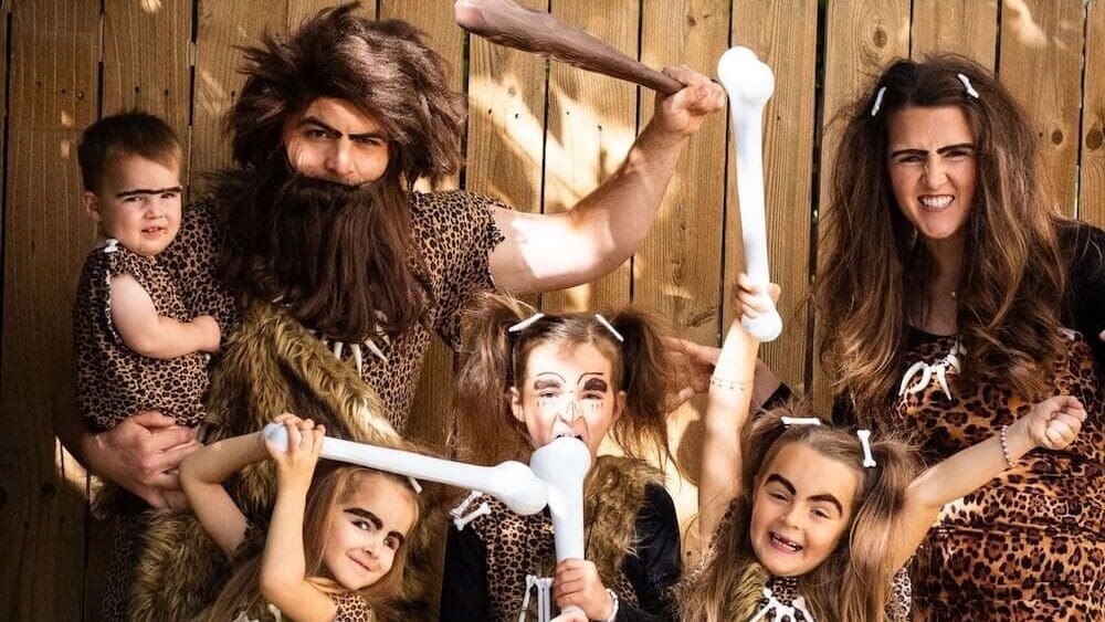Family in DIY caveman costumes with faux-fur accessories and oversized bone props.