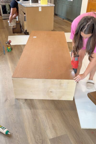 Crystel screwing a hardboard back panel onto the flipped plywood cabinet box for the DIY shelves and cabinets that are going in her dining room.