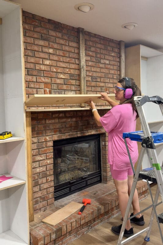Crystel setting a second board on top of the first to build the mantel to double thickness on the DIY fireplace built ins