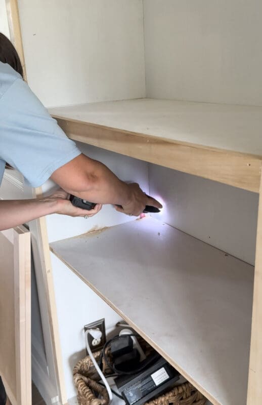 Crystel is using an oscillating multitool to cut the screws and brad nails holding a shelf in place.