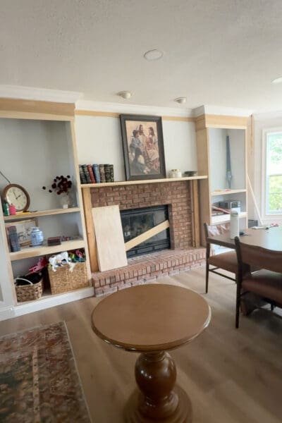 Built-in shelves and cabinets mid-build with trim partly installed and shelves holding books, baskets, and toys while the family lived around the unfinished project