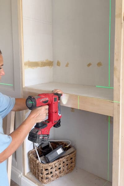 Crystel nailing the face frame back onto the cabinet opening after moving the shelf up higher.