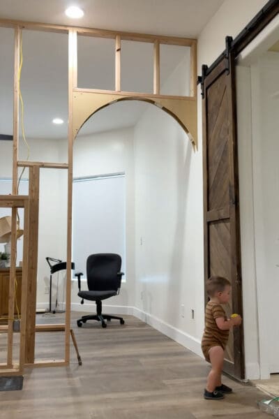 Framed room divider wall with a fireplace frame in the center and arch framing finished in the walkway openings on both sides