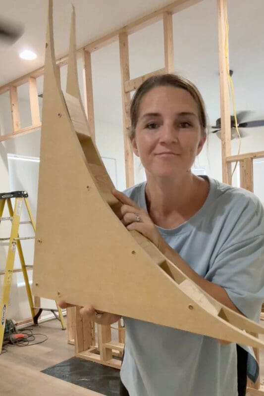 Crystel holding up a finished arch corner piece showing the smooth curve and screw holes along the face