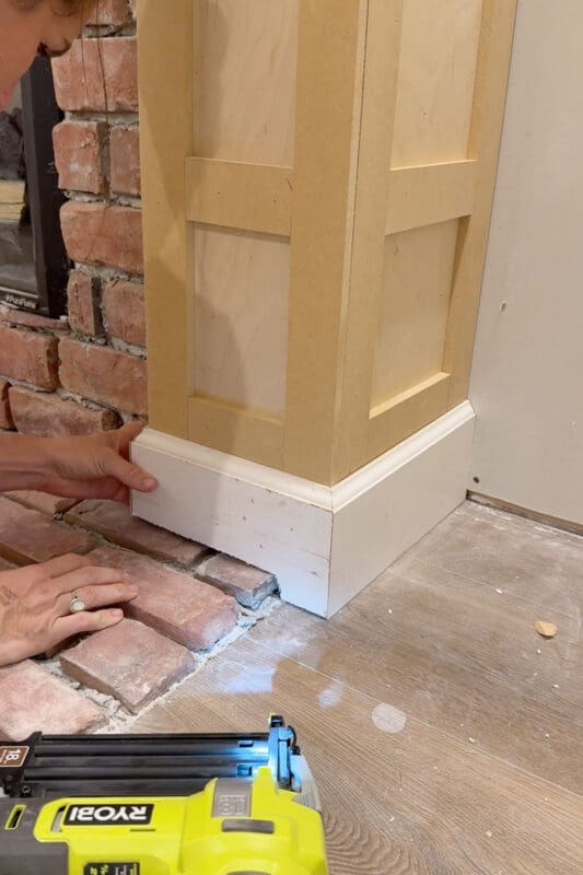 Crystel fitting baseboard around the base of the fireplace column, with the bottom edge cut to sit snugly over the uneven brick hearth