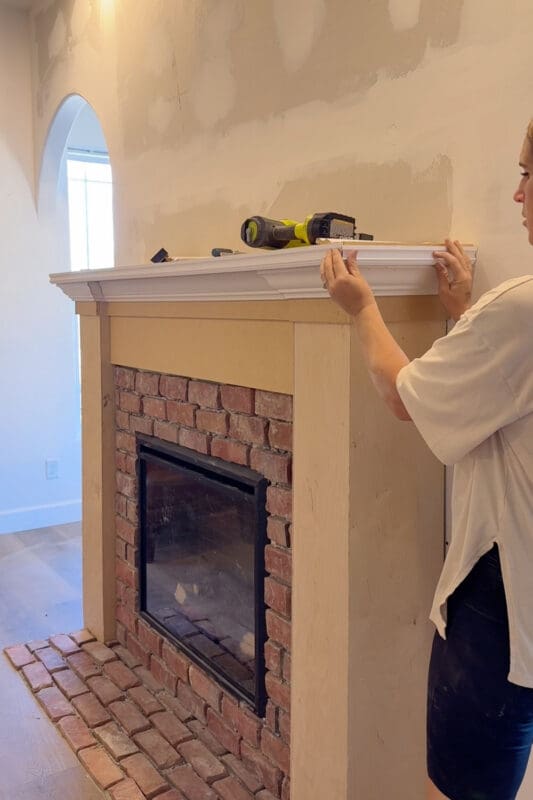 Crystel fitting cut-down baseboard trim along the edge of the double-stacked plywood mantel shelf for a clean, finished look