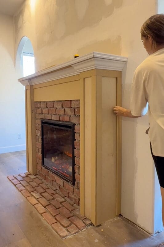 Crystel fitting a strip of MDF trim onto the front of the fireplace column as she begins adding box molding to the surround