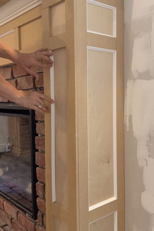 Crystel pressing thin white panel molding into the inside edges of the MDF box molding on the fireplace column for an extra layer of detail